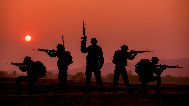 Military personnel silhouetted against sunset