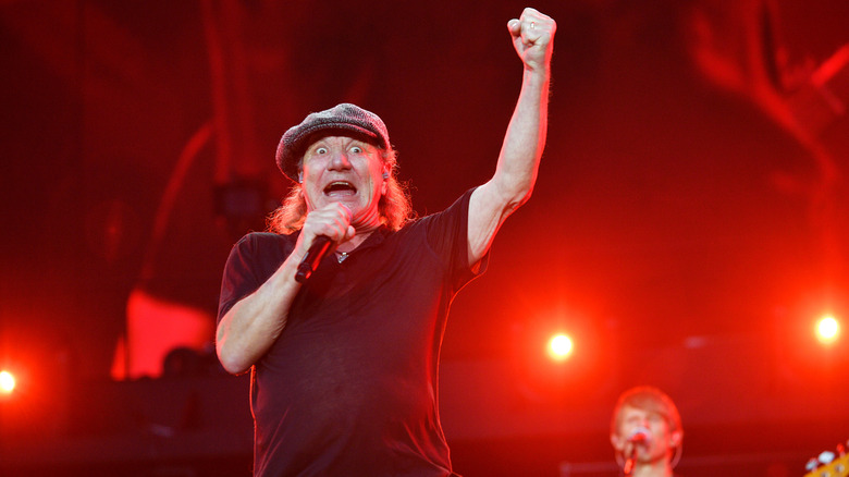 AC/DC's Brian Johnson raising his fist in the air and singing during a Wembley Stadium concert in 2024