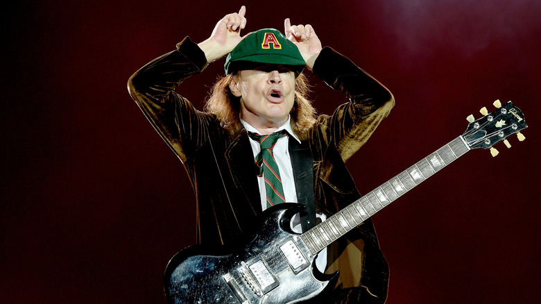 AC/DC's Angus Young dressed as a schoolboy and doing the devil horns during a concert in 2015