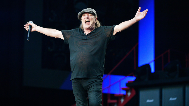 AC/DC's Brian Johnson standing with his arms wide open on stage at Wembley Stadium in 2024