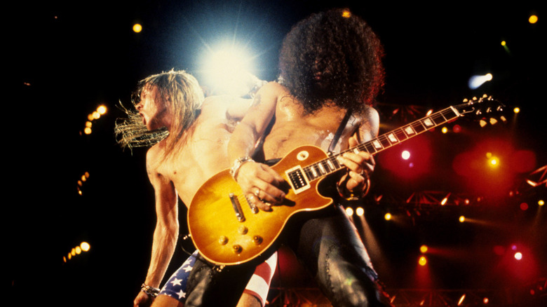 Axl Rose and Slash guitar backlit on stage