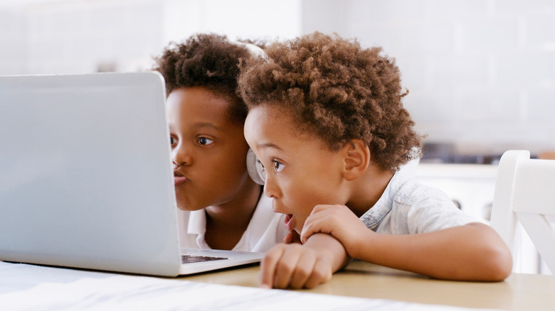 two kids looking at a laptop