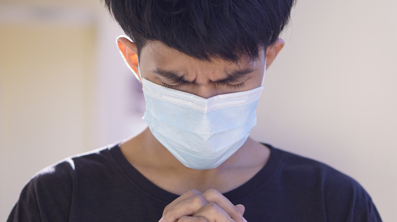 Teenager praying in mask