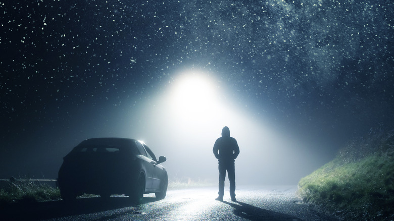 Silhouette of a man staring at a bright light in the night sky