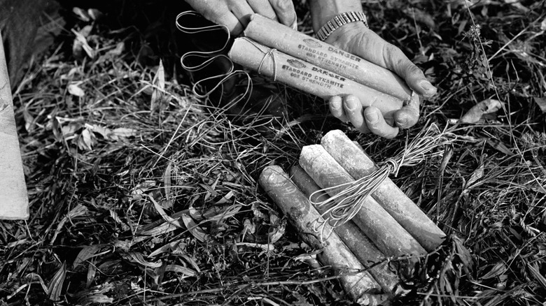 Old photograph of man handling sticks of dynamite