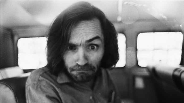 Charles Manson in car raising eyebrow