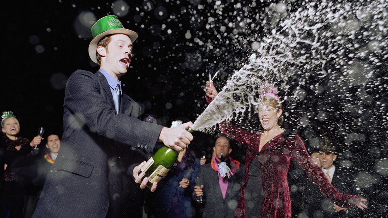 Person at party uncorks champagne bottle