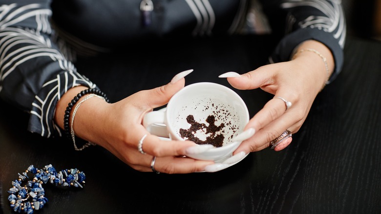 Woman holding cup with tea leaves