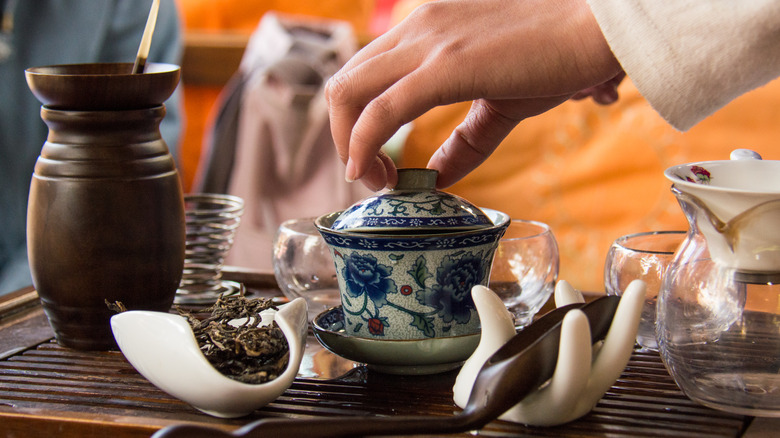 Hand lifts lid blue and white teapot