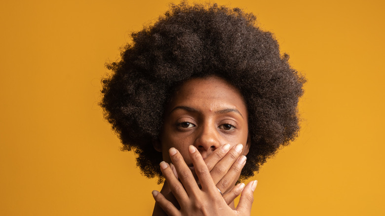 A woman with her hands over her mouth