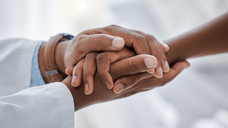 doctor holds patient's hand