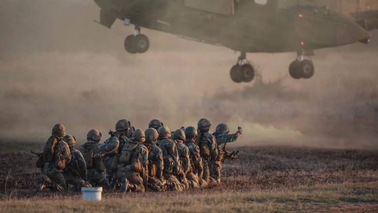 military soliders crouching helicopter