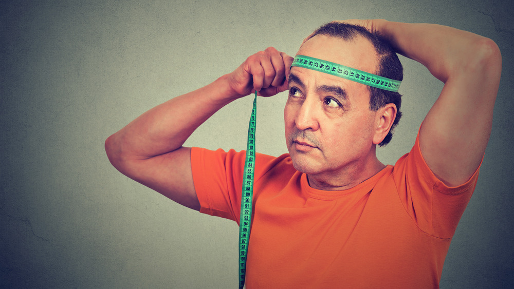 man measuring his head