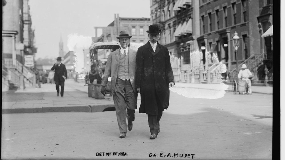 Dr. Ernest Muret (right) being escorted by police