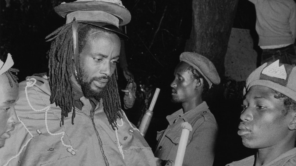 Kenyan revolutionary leader, Field Marshal Musa Mwariama (1928 - 1989, left) of the Mau Mau movement, inspecting a final guard of honour at a forest base, before his forces surrender their arms following Kenya's independence