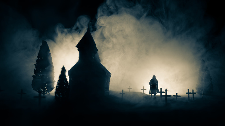 Silhouette of woman with cane in graveyard