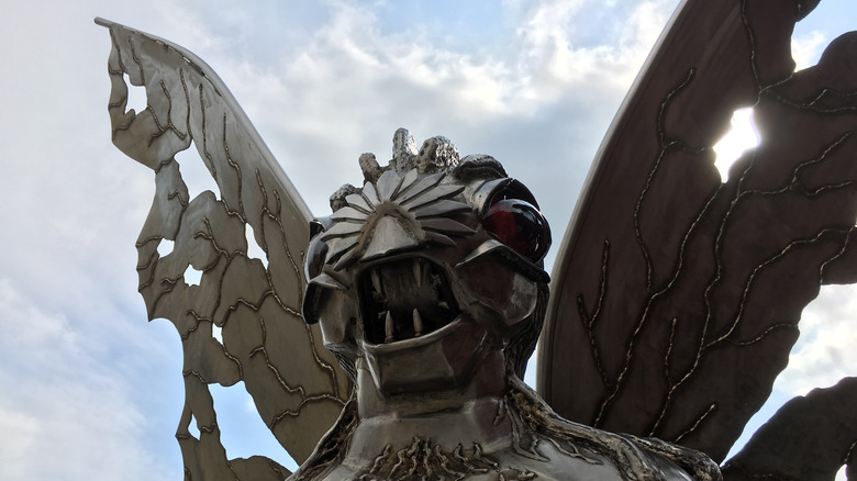 Metal Mothman statue with clouds behind it