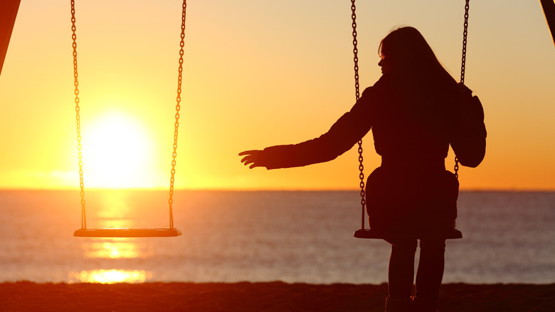 Woman reaching for empty swing