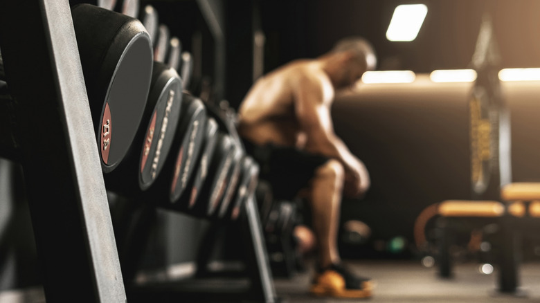 Men sits by weight rack