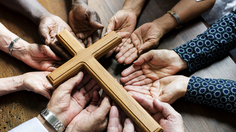 People of different races praying with cross