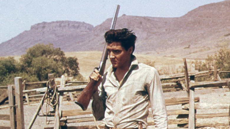 Elvis Presley shoulders a rifle