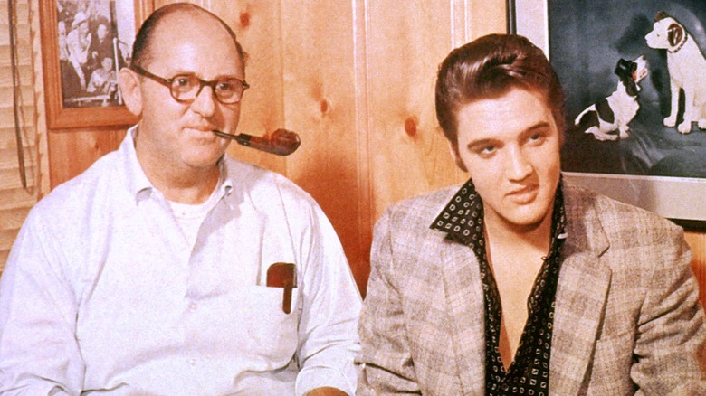 Colonel Parker holds a pipe while Elvis smiles