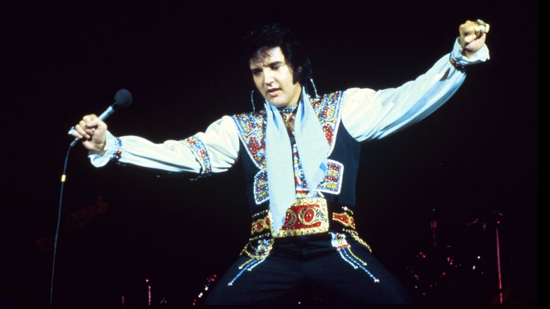 Elvis kneels and spreads his armshttps://time.com/6191111/elvis-priscilla-presley-true-story/