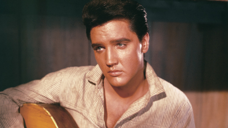 Elvis sat playing guitar looking forlorn