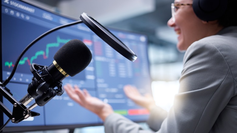 Woman microphone stock market prices in background