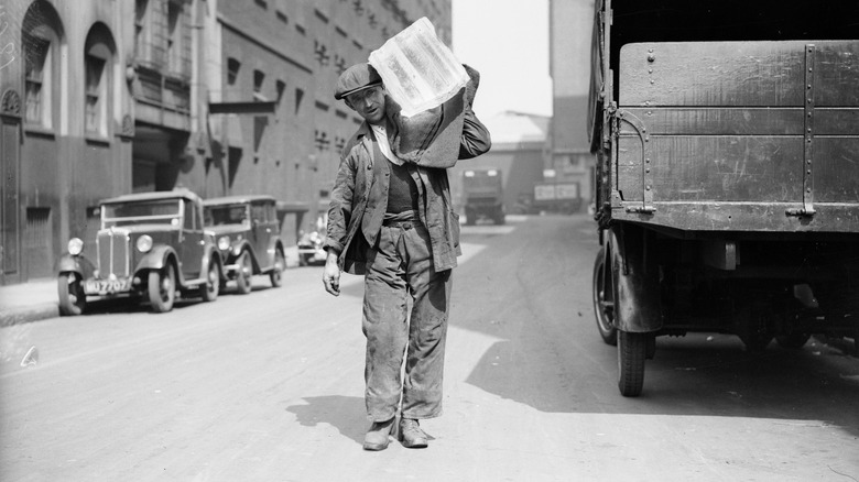 A worker carrying a block of ice in 1936