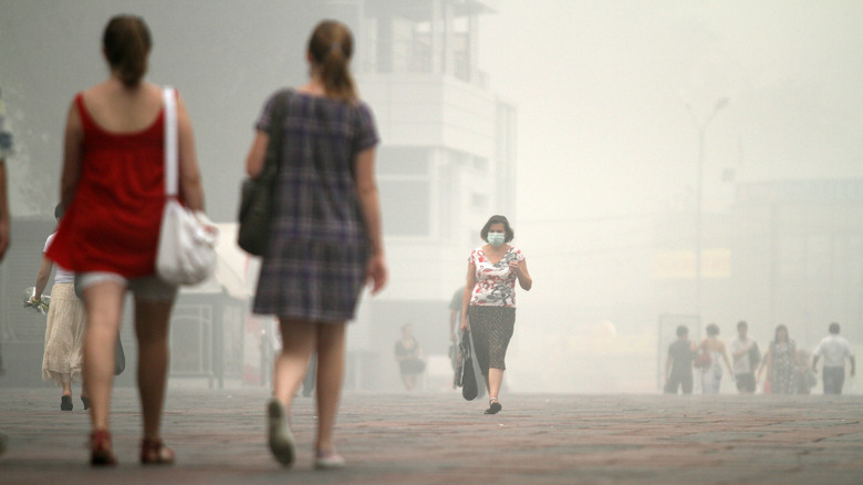 Pedestrians walk through smog