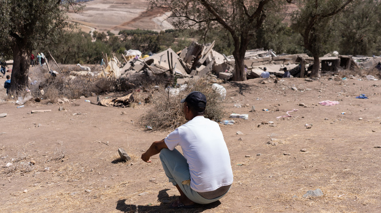 person looking at the ruins of his village