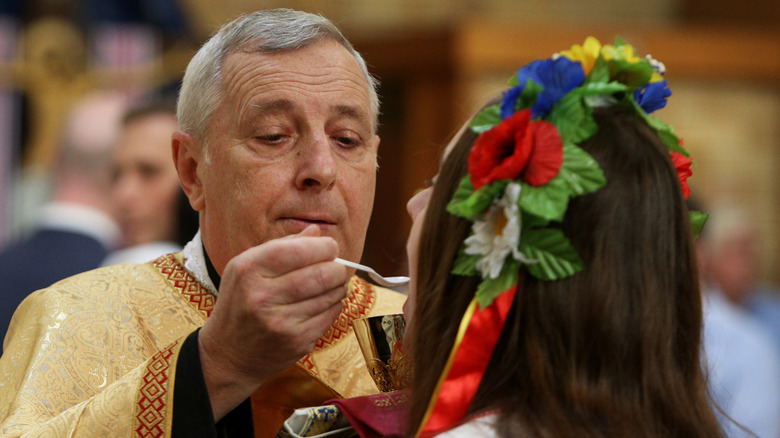 A woman in a traditional headdress receiving Ukrainian Catholic Communion