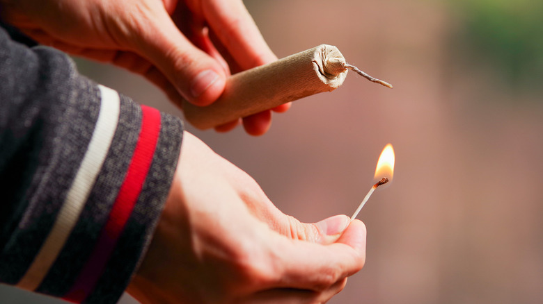 A person lights a firecracker