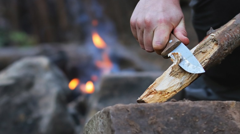 Man cuts wood for campfire