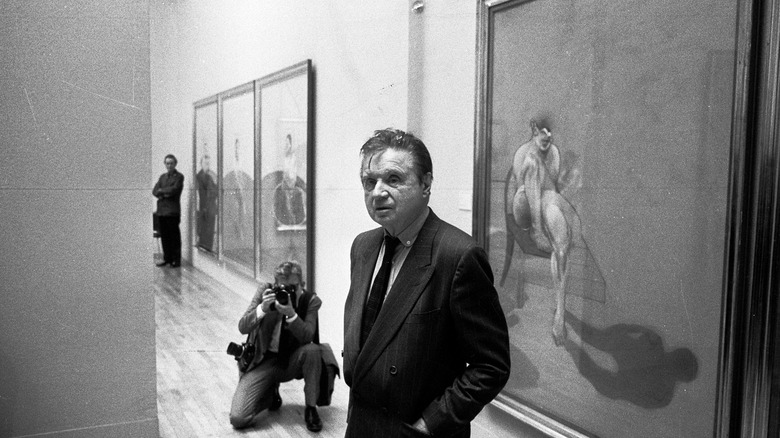 Francis Bacon standing before paintings