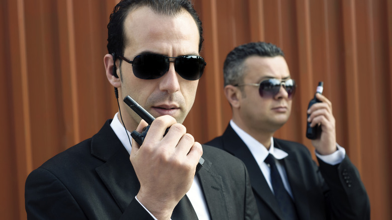 men in black suits with sunglasses and walkie talkies