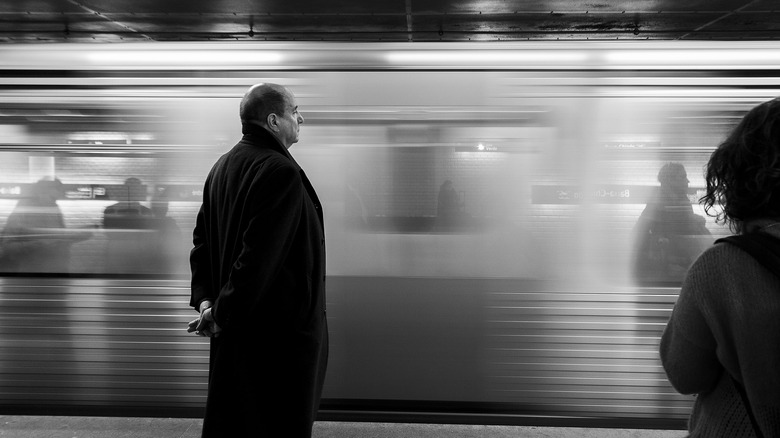 bald man in black suit on subway platform