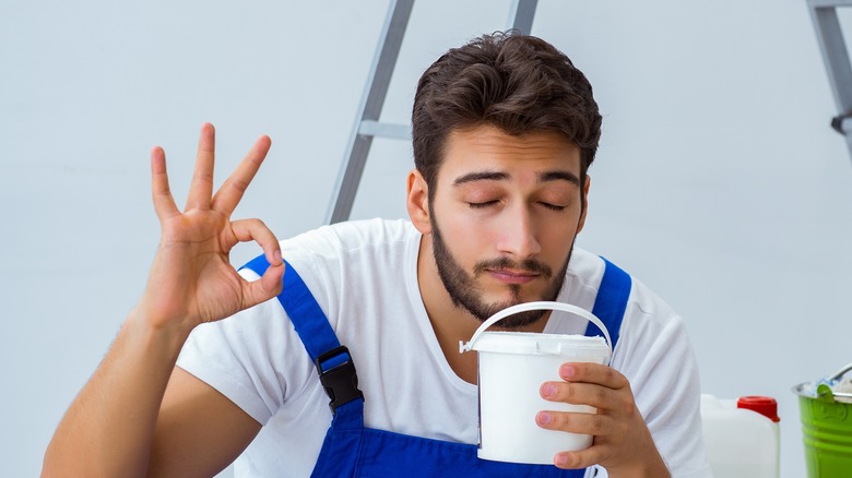 Guy giving 'okay' sign while smelling glue