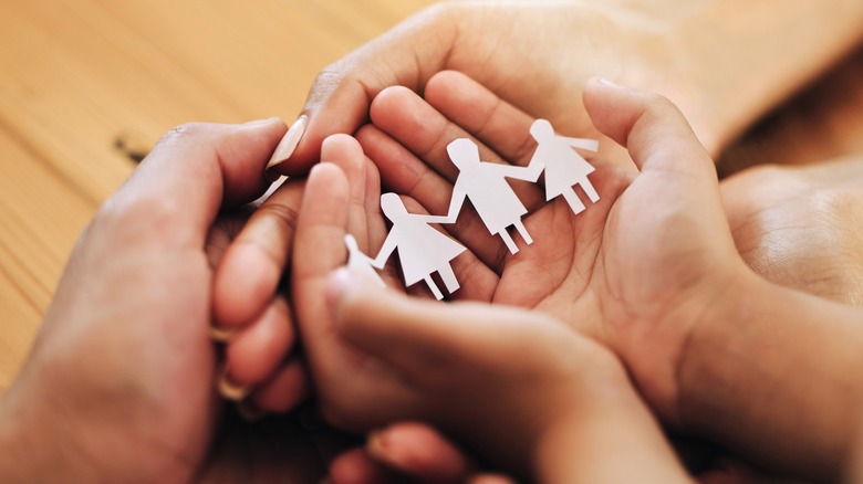 Hands holding paper cutout of family