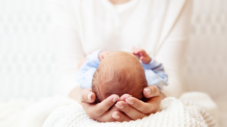 Mother cradling newborn in hands