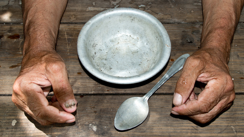 unhoused man with empty bowl