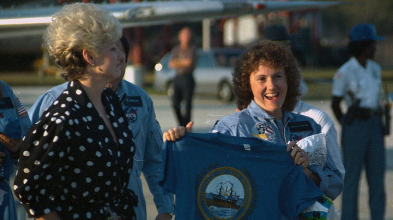 christa mcauliffe holding shirt and smiling