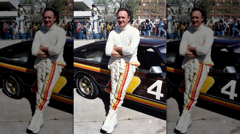 Gene Hackman posing in front of a race car