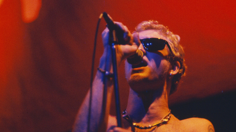 Layne Staley looking up while singing in sunglasses on red lit stage