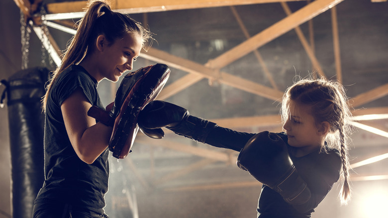 Child practising boxing female instructor