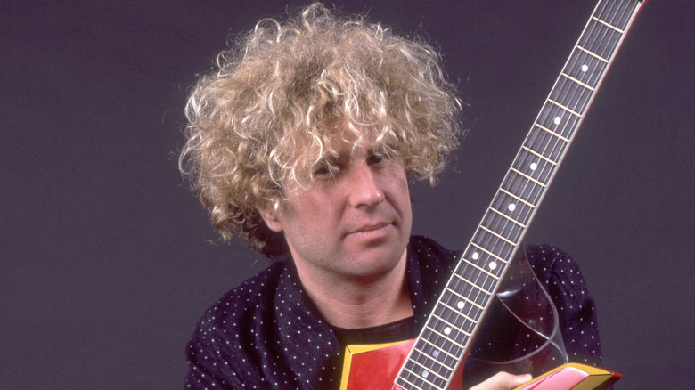 sammy hagar looking askance while holding a guitar in the 80s