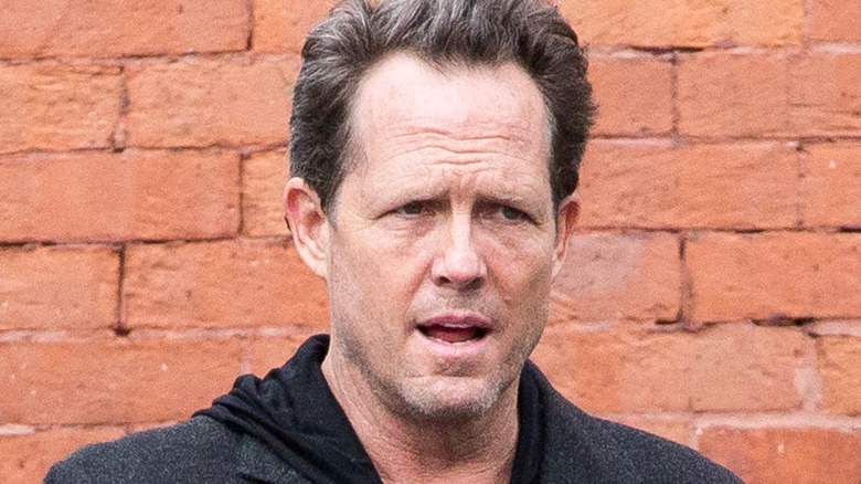 dean winters walking past brick wall