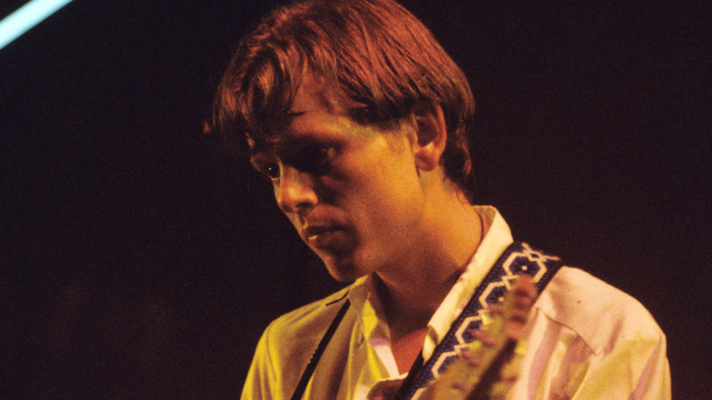 ricky wilson playing guitar onstage with b-52's and looking off