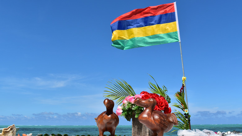 Small wooden dodo statues with flag of Mauritius on beach